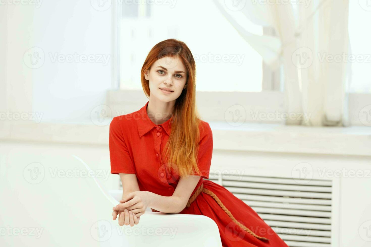 red-haired woman in red dress sitting on a chair fashion photo