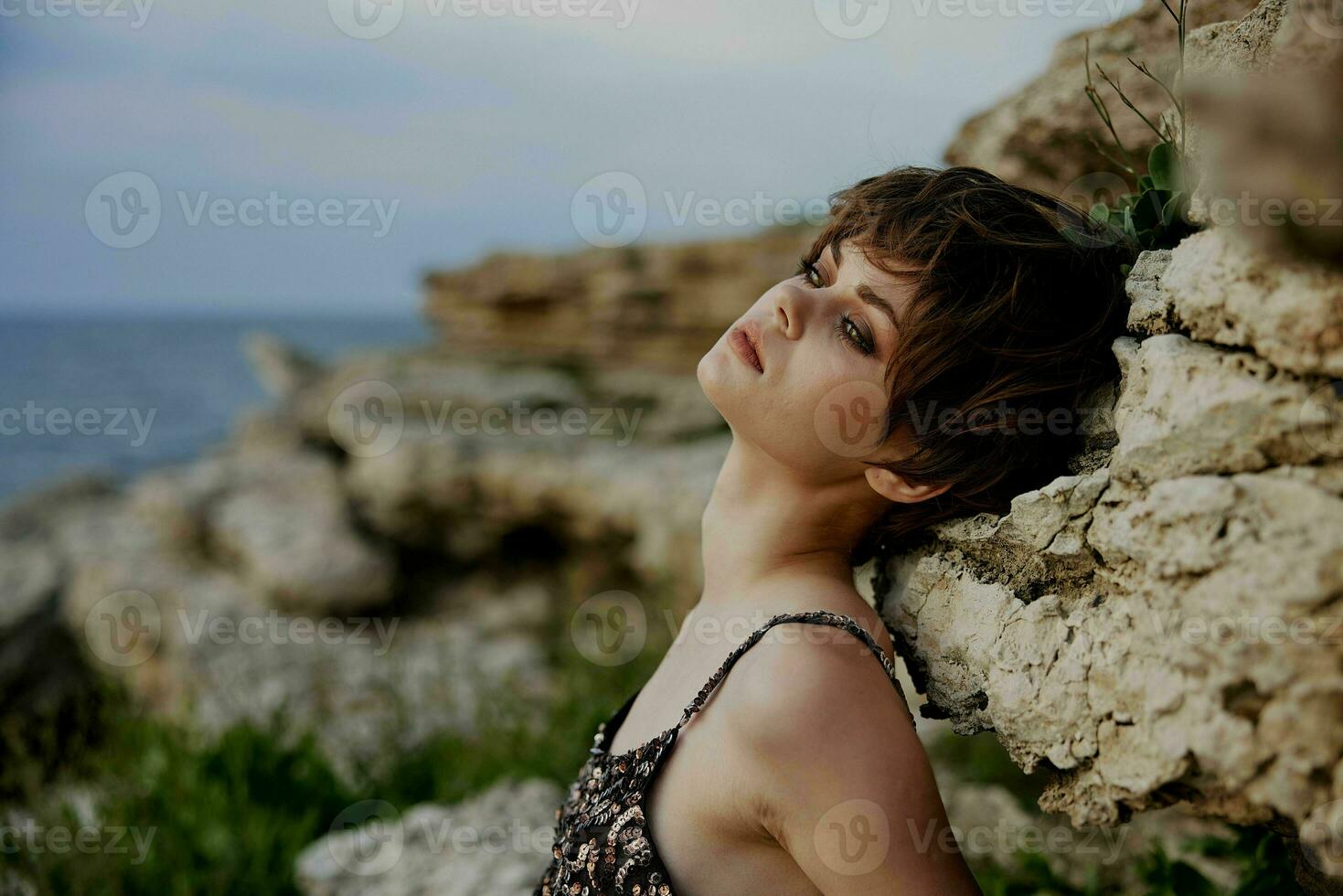 woman with short hair makeup posing on stone rock photo