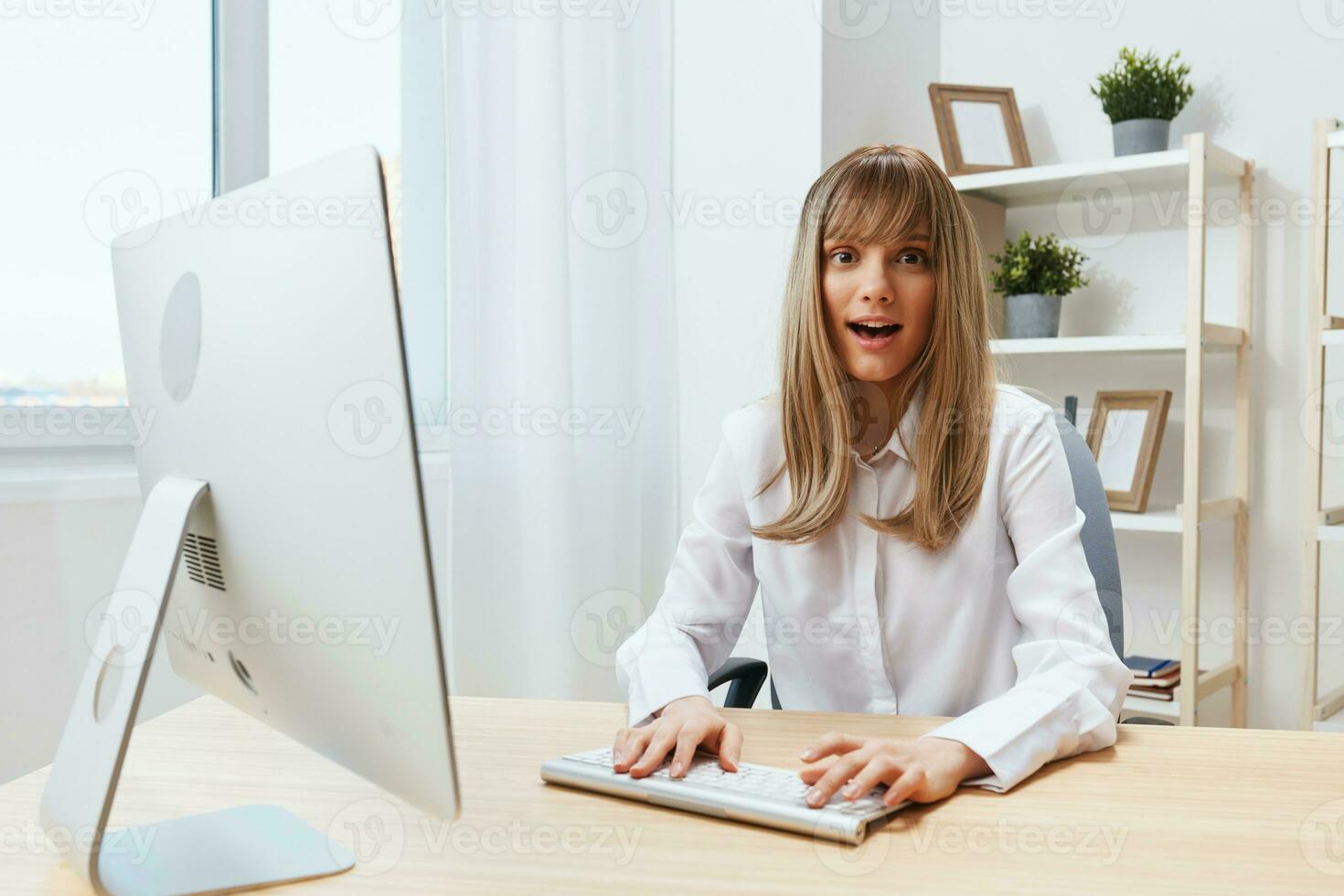 Smiling cheerful adorable blonde businesswoman worker freelancer look at camera typing project report in light modern office. Happy employee work on computer online in support service. Copy space photo