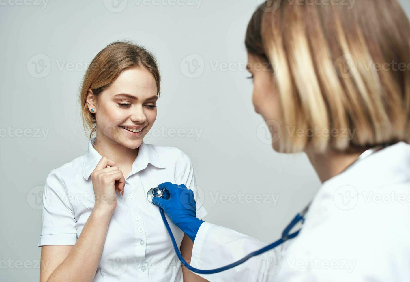 médico con un estetoscopio y un contento paciente en un ligero antecedentes foto