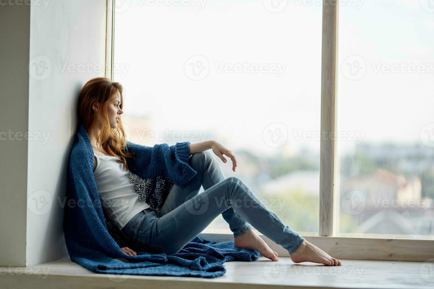 hermosa mujer sentado cerca el ventana con un azul tartán descanso foto