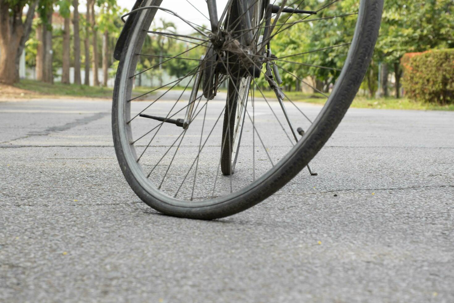 Closeup view of vintage bike which has flat wheels and parked on cement floor of street near the building, soft focus. photo