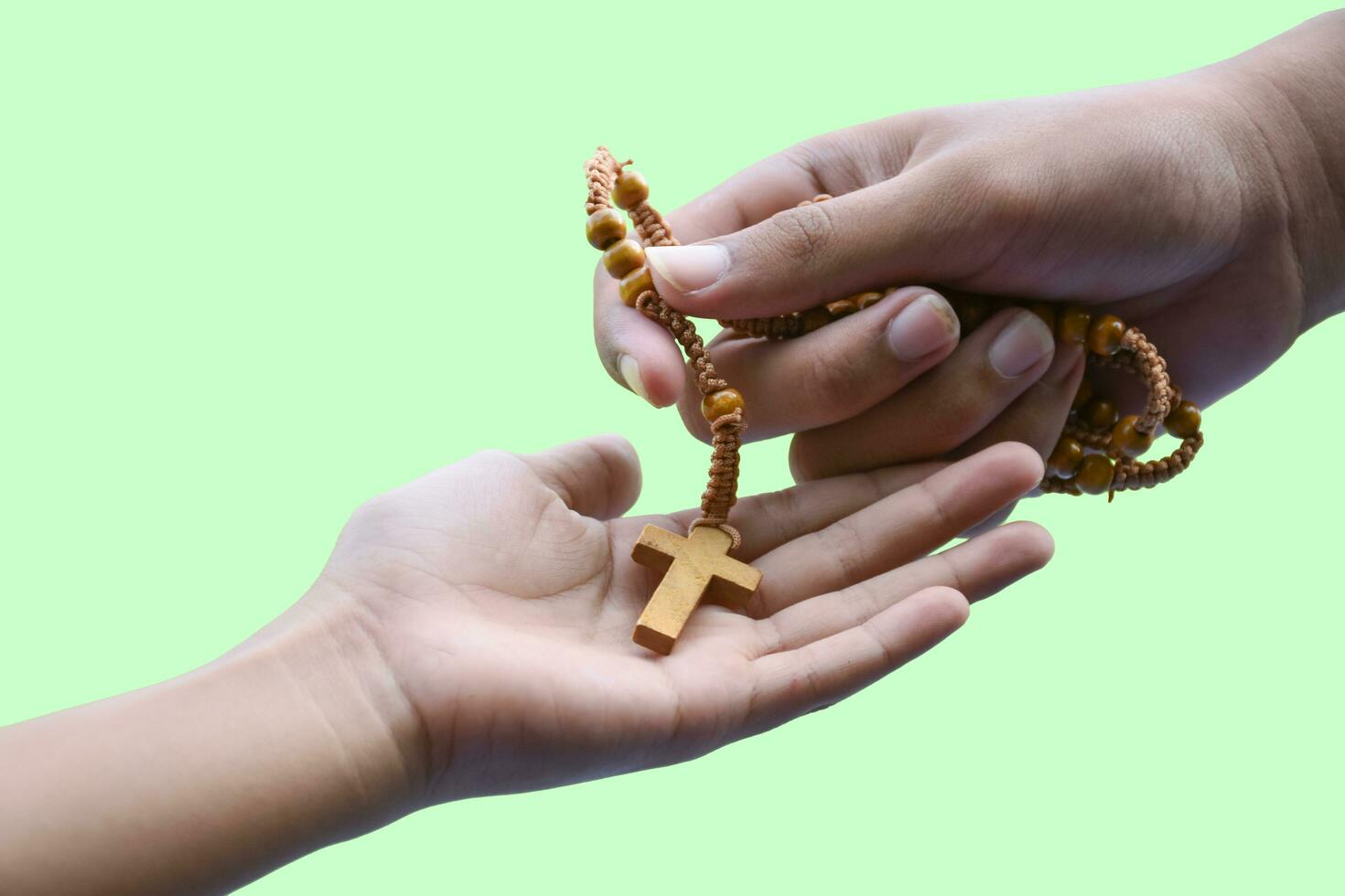 Hands holding wooden cross rosary isolated on green background with clipping paths. photo