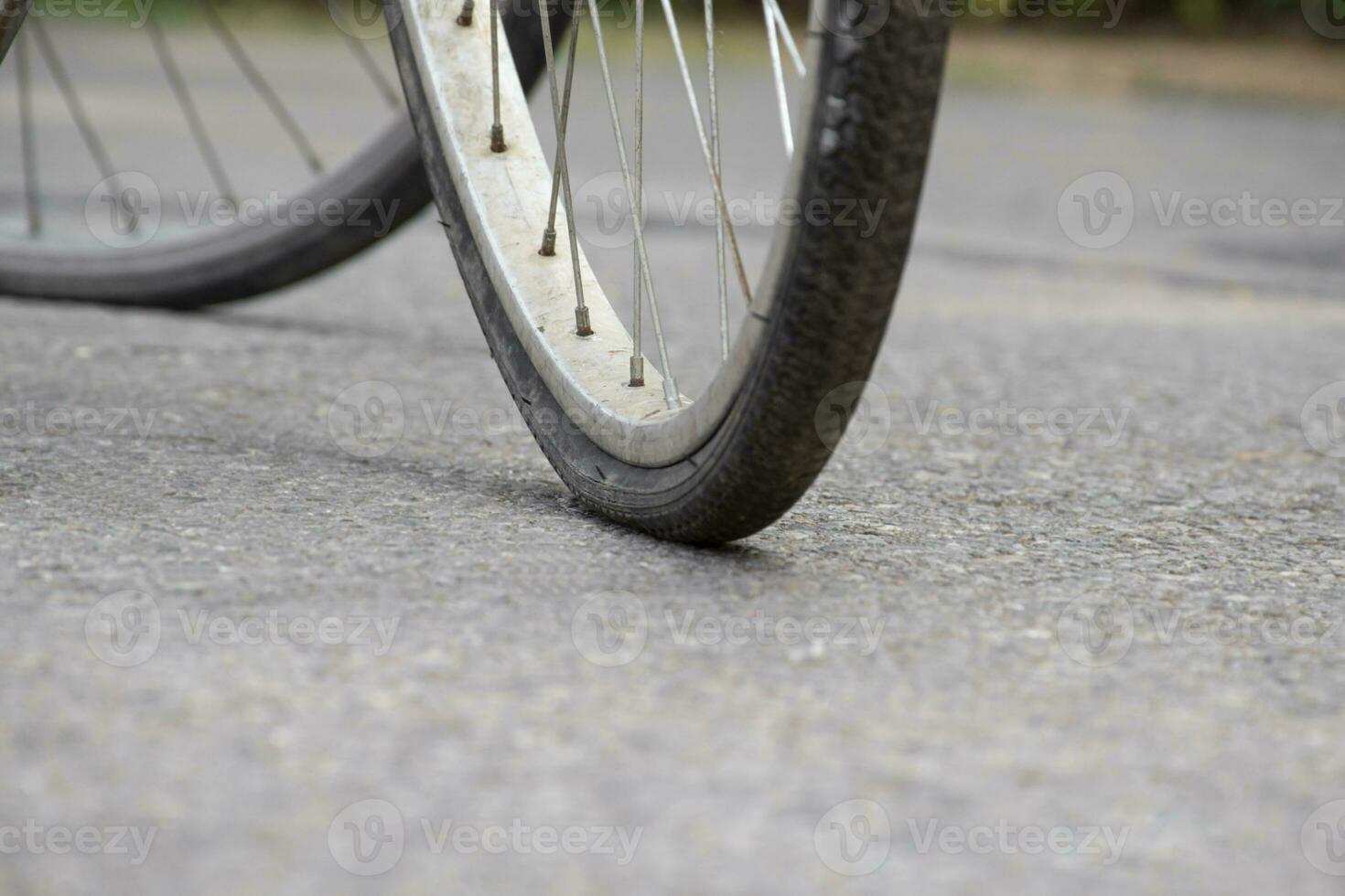 An old bike which has flat tires and parked by the urban road and waited to fix or to change the new one and to refill the air inside, soft focus. photo