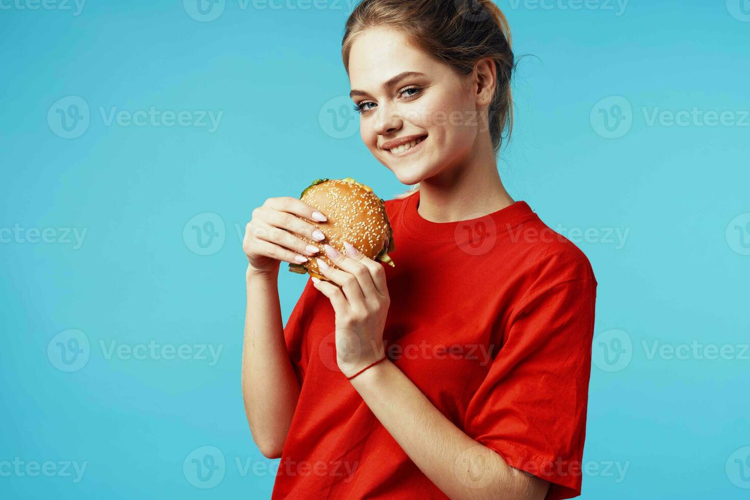 cheerful woman in red t-shirt hamburger in hands fast food blue background photo