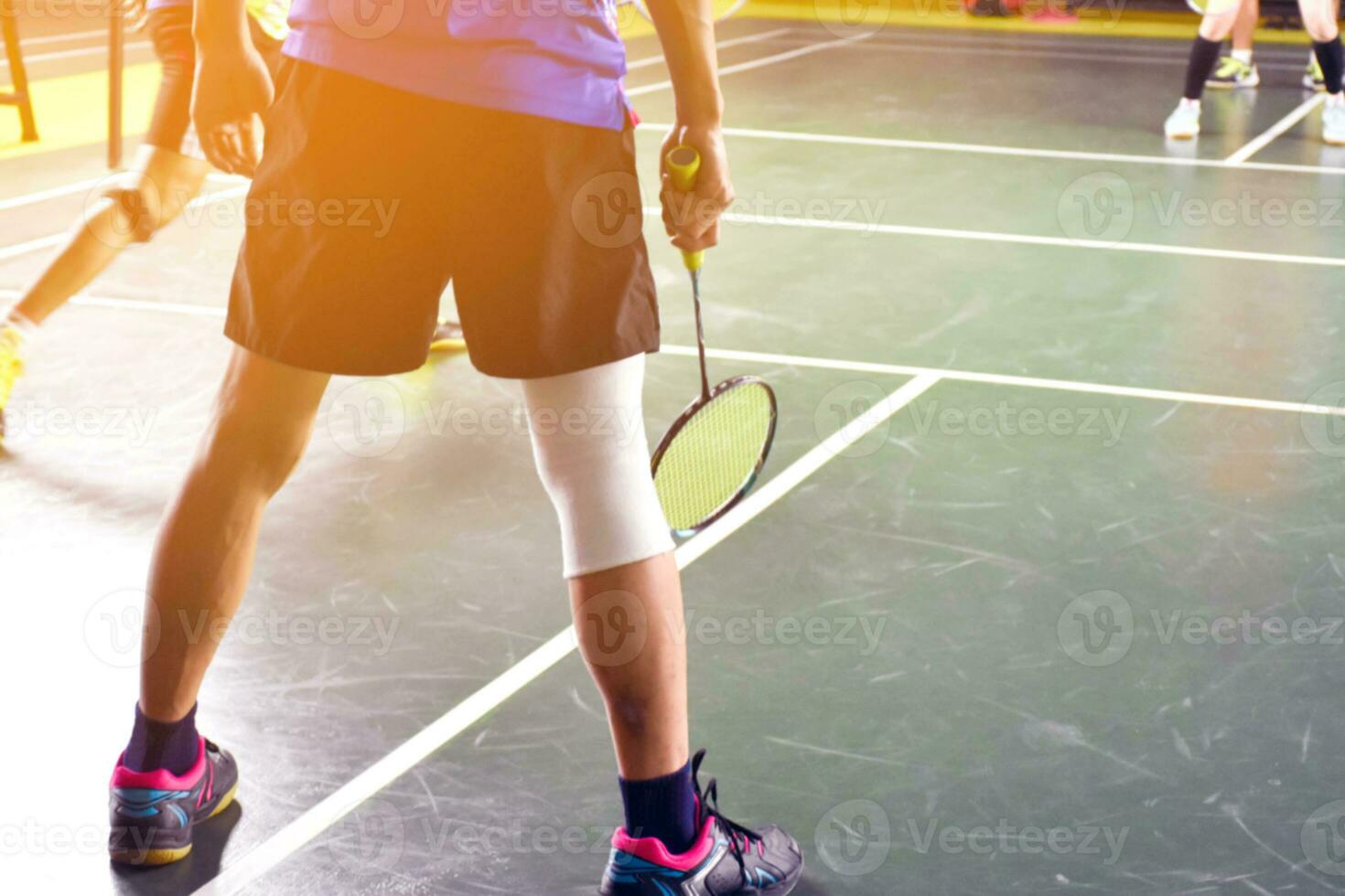 A badminton athlete wraps his right knee with a white knee bandage to
