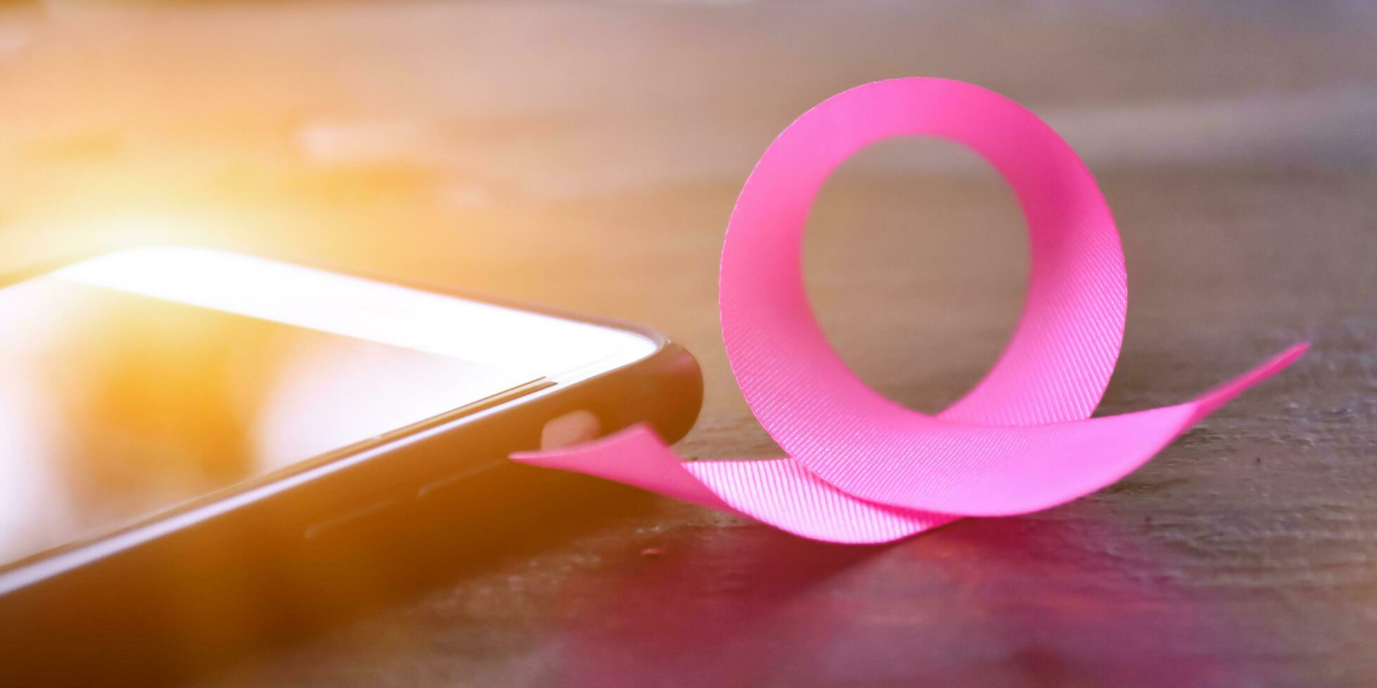 Pink ribbons on wooden table, sunlight and blurred background, concept for breast cancer awareness around the world. Soft and selective focus on pink ribbons. photo