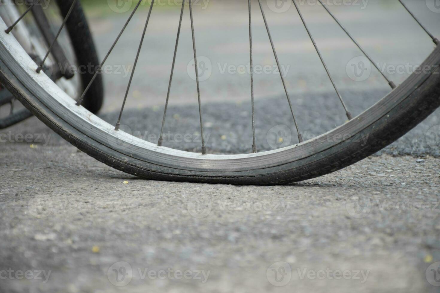 An old bike which has flat tires and parked by the urban road and waited to fix or to change the new one and to refill the air inside, soft focus. photo