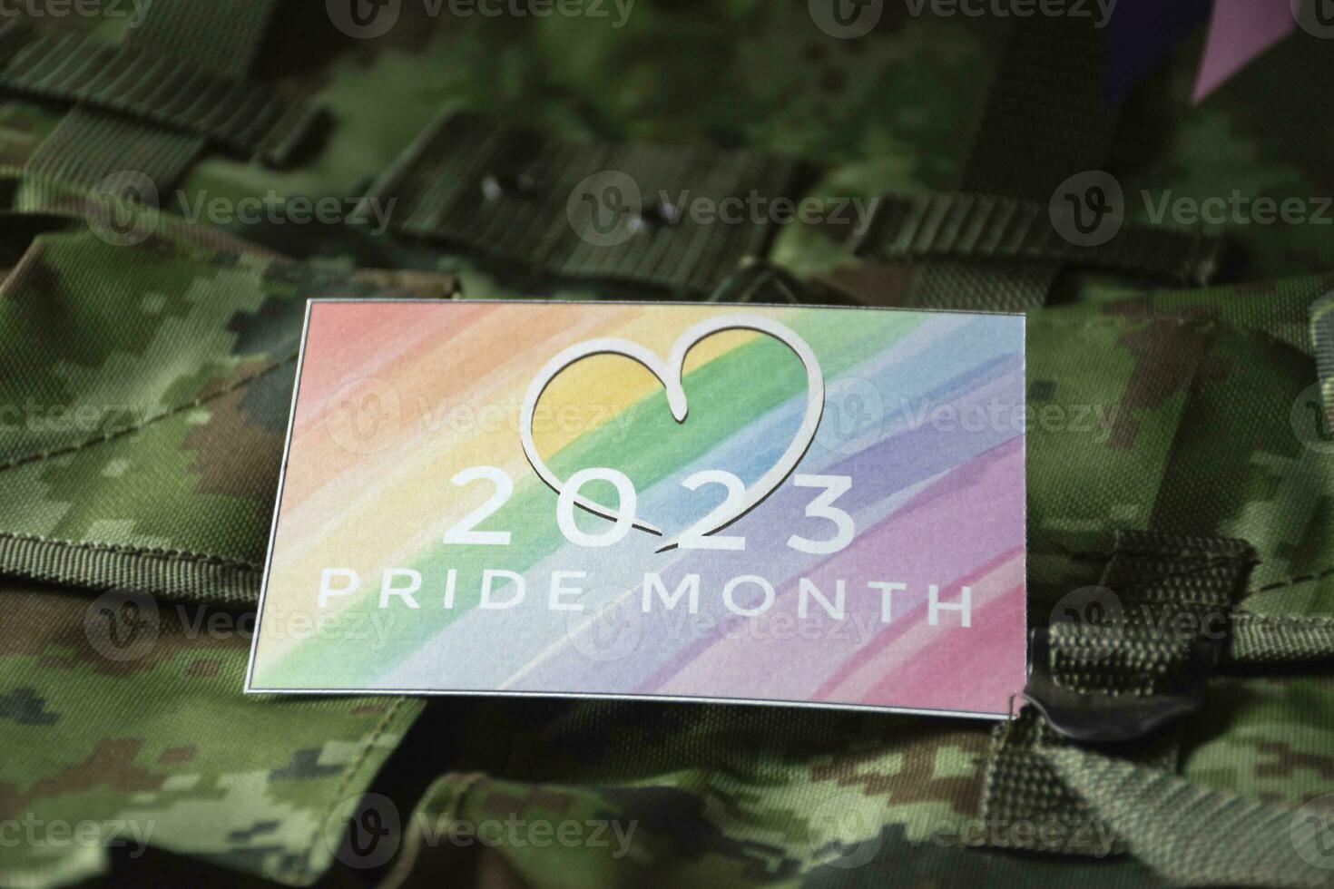 '2023 Pride Month' card on camouflage backpack of soldier, concept for calling out to respect gender diversity and to invite all people to enjoy LGBTQ events around the world in pride month. photo