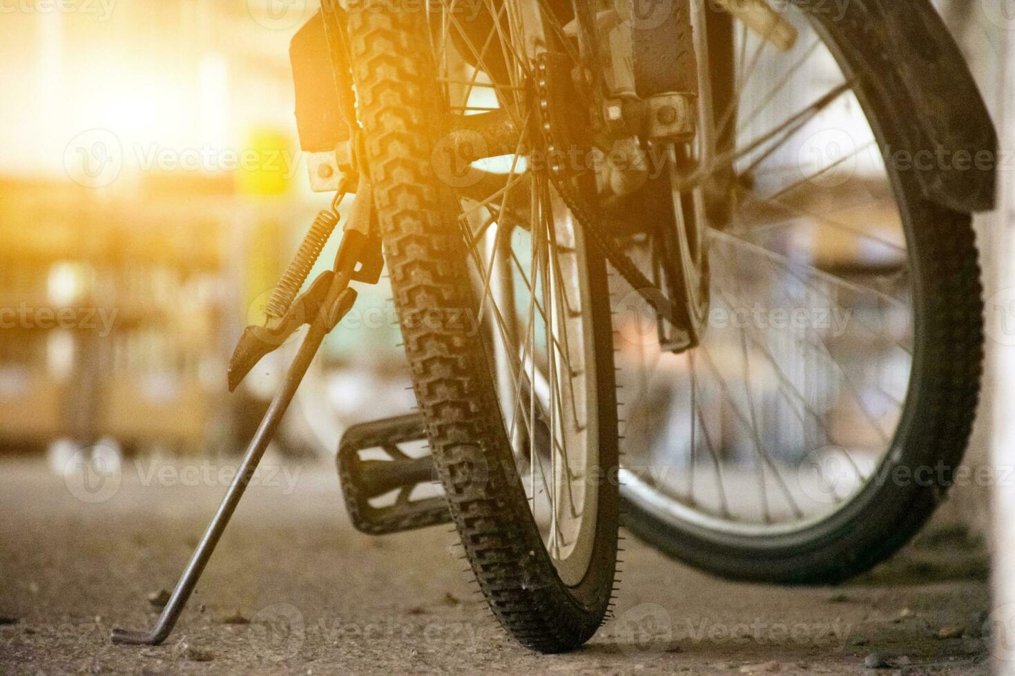 Closeup view of vintage bike which has flat wheels and parked on cement floor of downstairs of the building, soft focus. photo