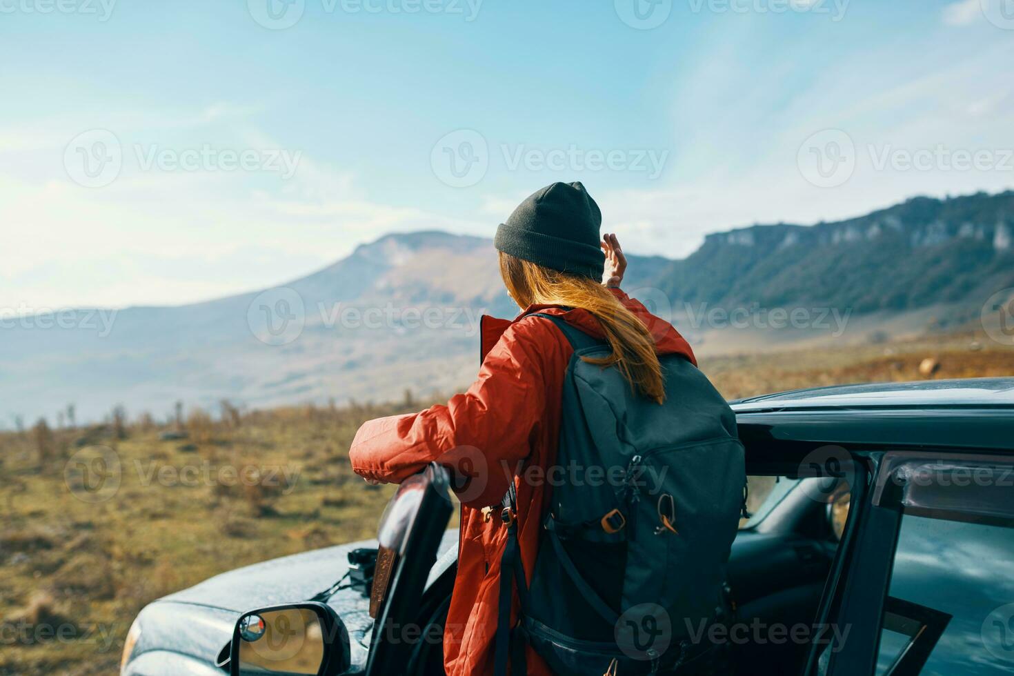 woman hiker in the mountains on nature near the car with a backpack on the back photo