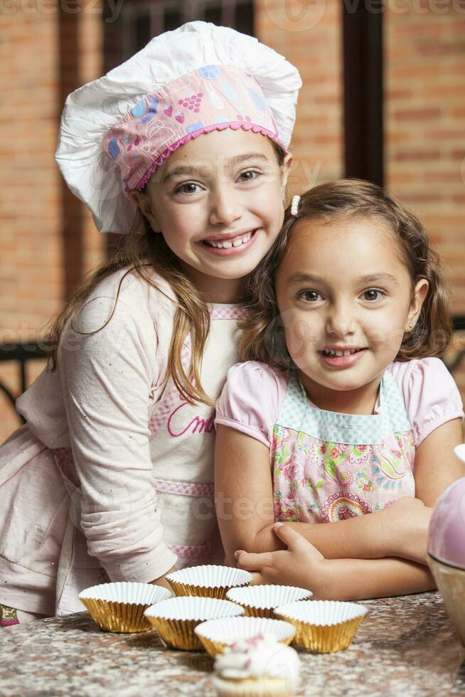 Sisters having fun baking cupcakes together at home. photo