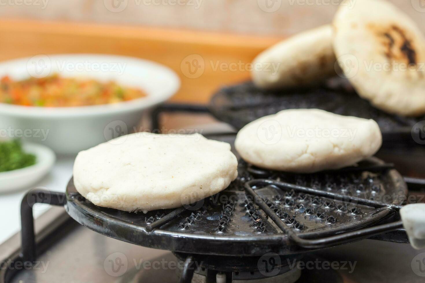 Colombian arepas being roasted on a round grill photo