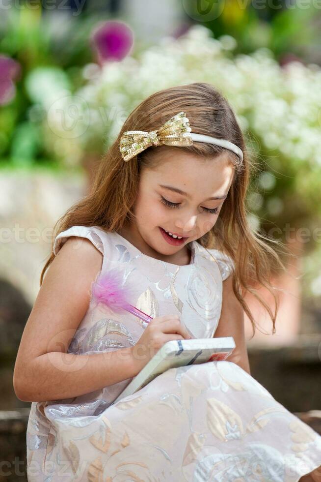 pequeño rubia niña escritura al aire libre foto