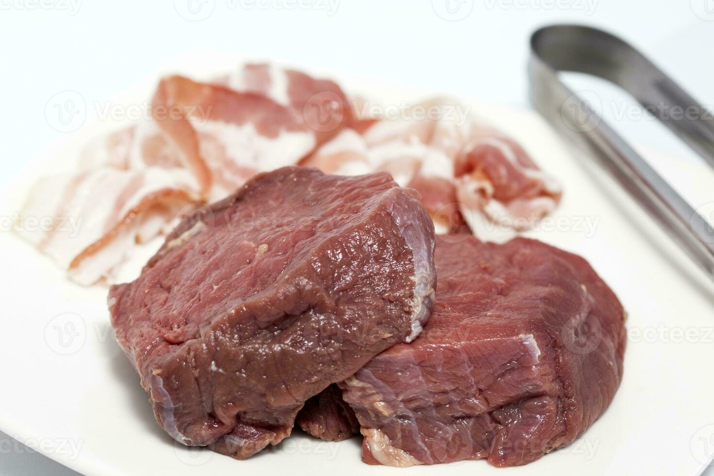 Raw medallions of beef tenderloin and pork bacon. Filet mignon preparation. photo