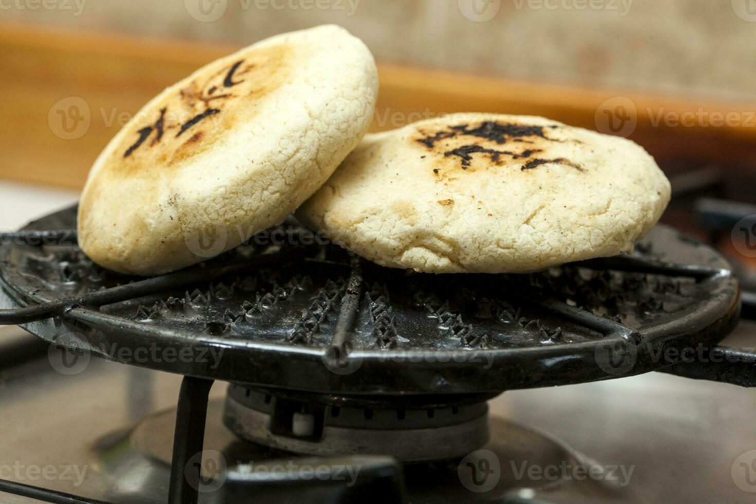 Stuffed Colombian arepa preparation. Colombian arepas being roasted on a round grill photo