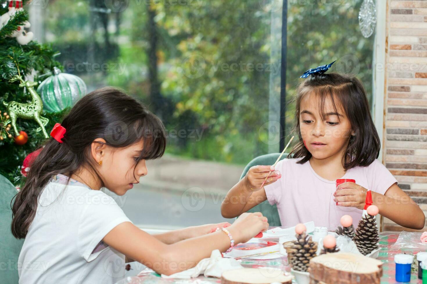 dos pequeño hermanas teniendo divertido mientras haciendo Navidad natividad artesanía con a hogar - real familia foto