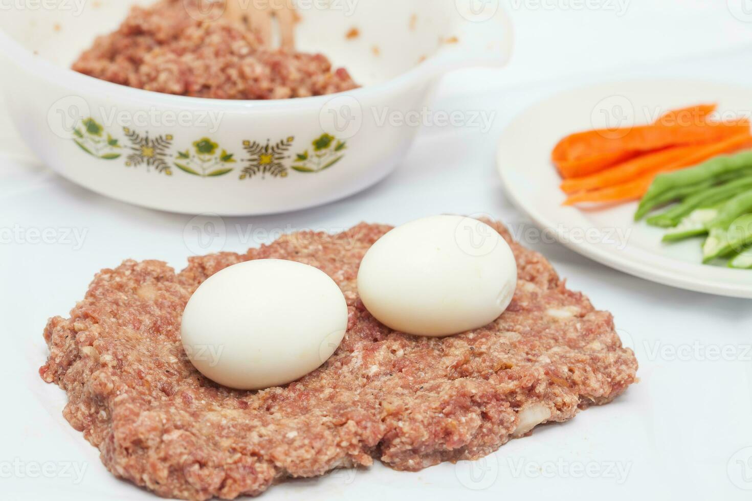 Preparation of a baked egg and vegetables stuffed meatloaf covered with bacon. Meat roll photo