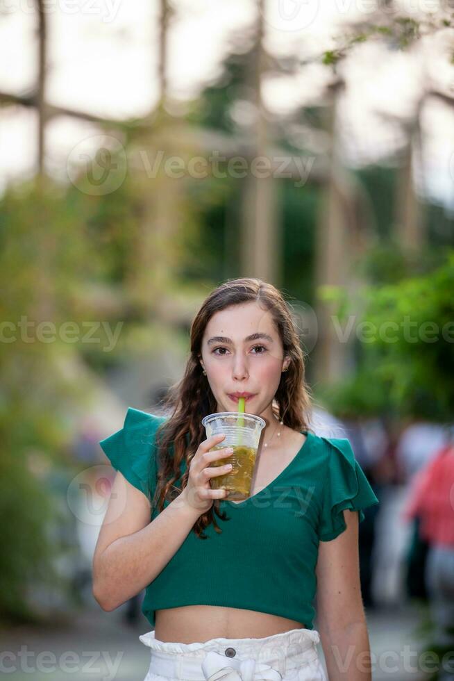 Beautiful tourist girl drinking a traditional Lulada at the Jairo Varela Square in the city of Cali in Colombia photo