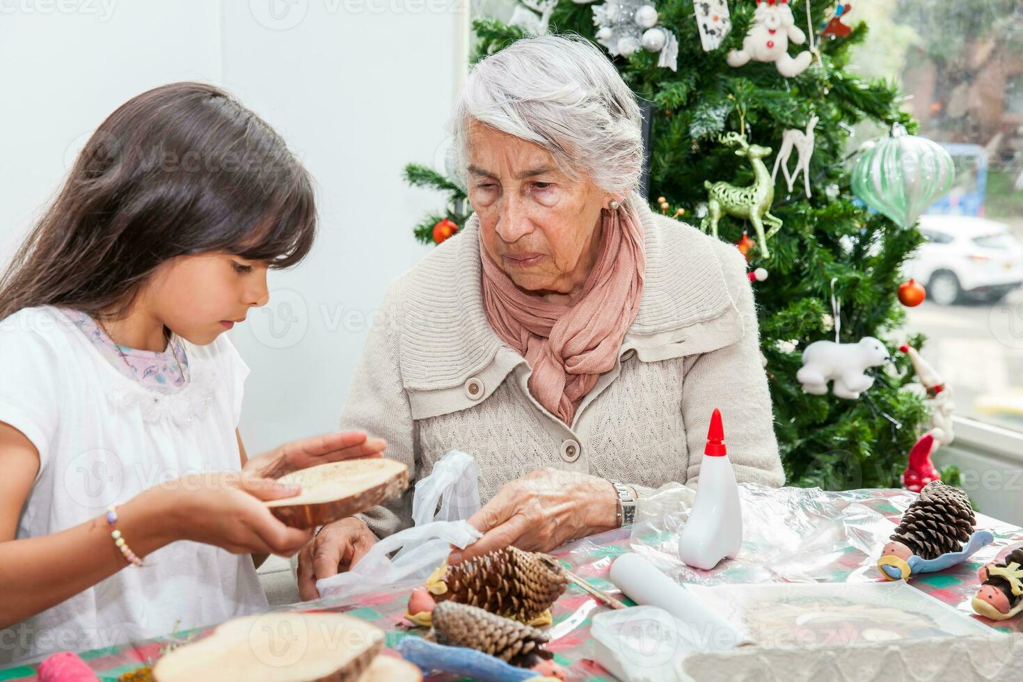 Grandmother teaching her granddaughter how to make christmas Nativity crafts - Real family photo