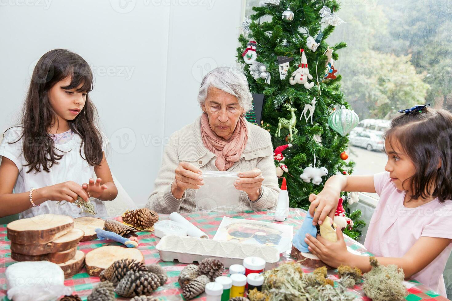 Grandmother teaching her granddaughters how to make christmas Nativity crafts - Real family photo