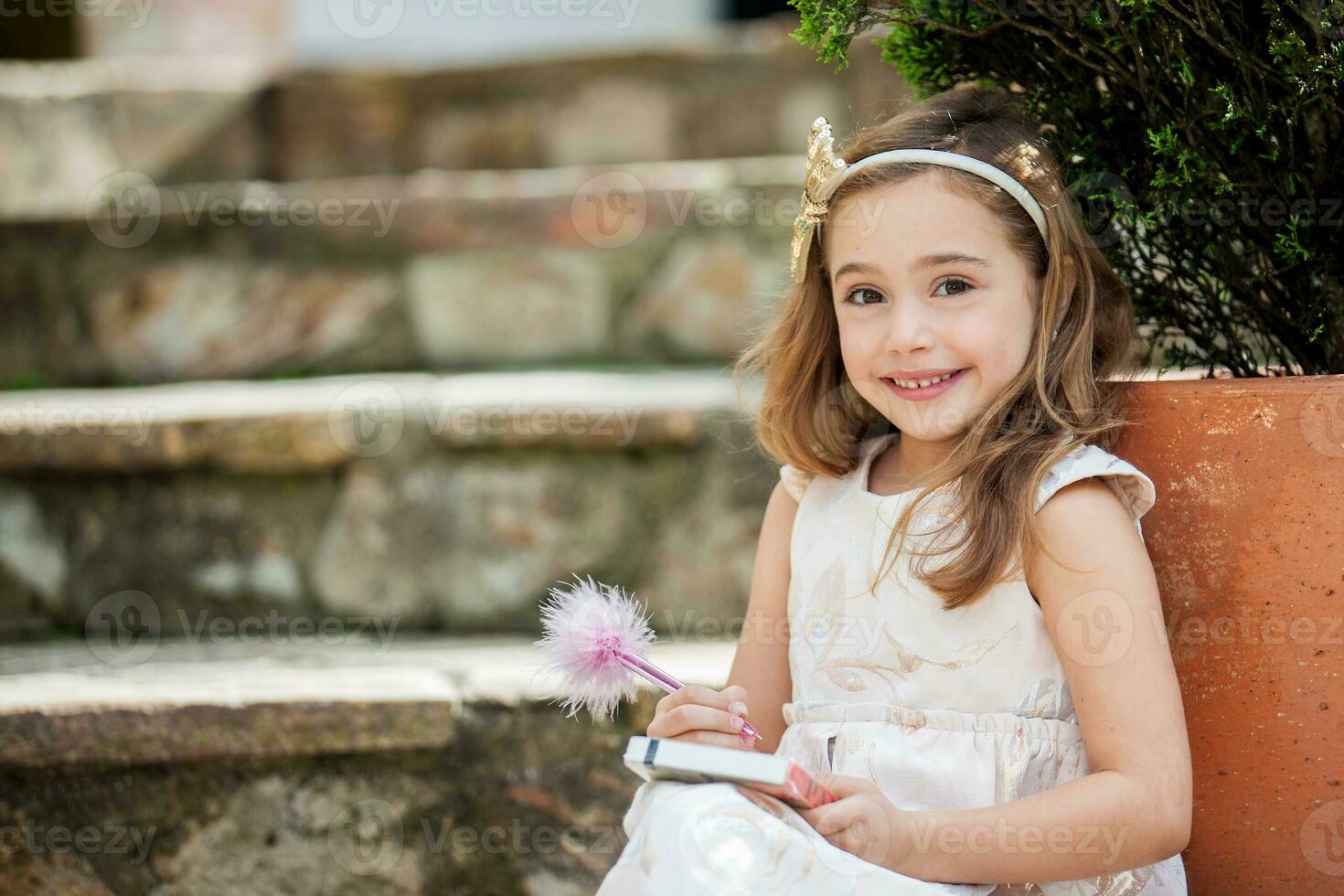 Little blonde girl writing outdoors photo