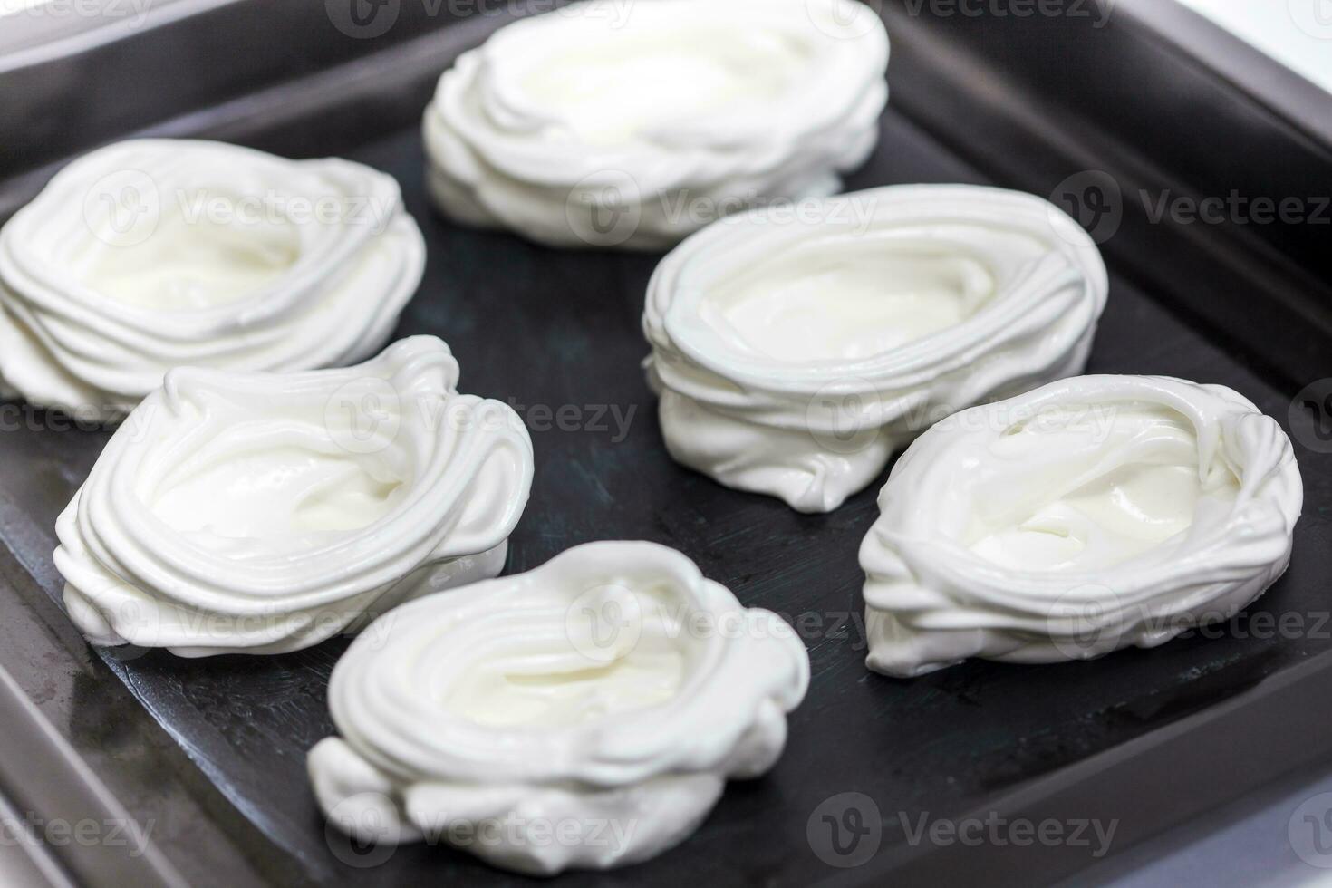 Raw meringues on baking sheet photo