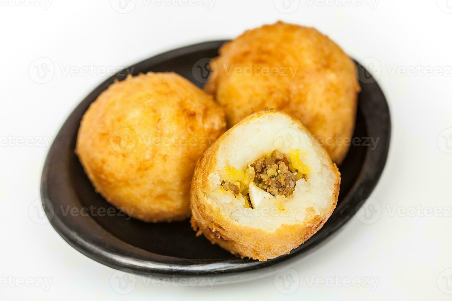 Preparation steps of traditional Colombian dish called stuffed potatoes. Ready stuffed potatoes served in a black ceramic dish isolated on white background photo
