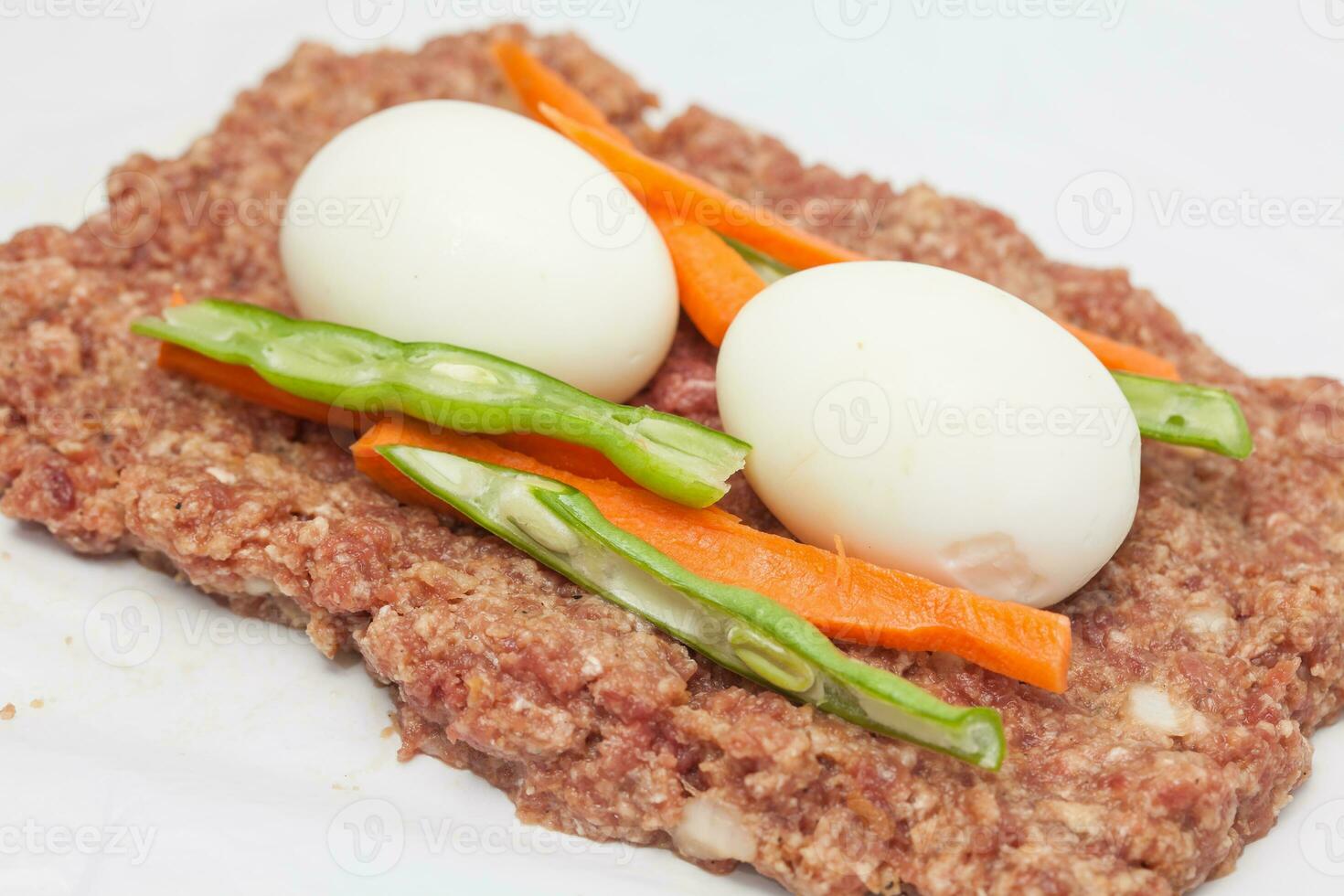 Preparation of a baked egg and vegetables stuffed meatloaf covered with bacon. Meat roll photo