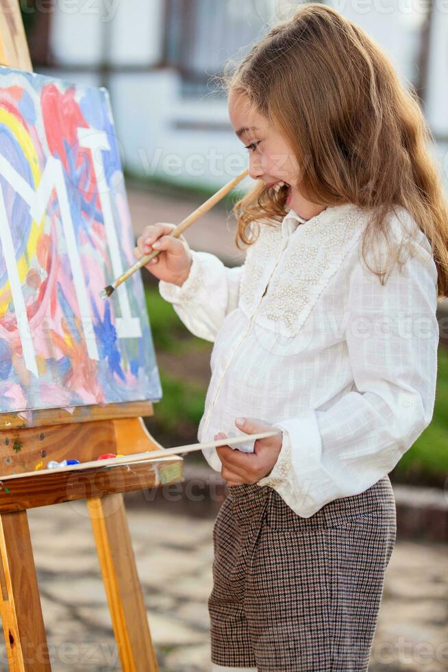 Little blonde girl painting outdoors photo