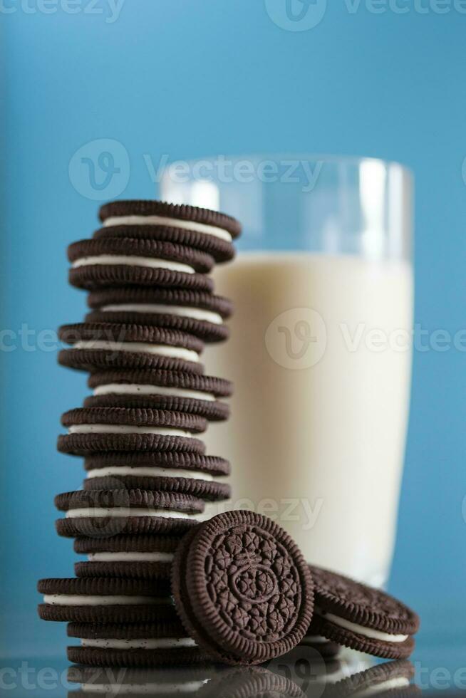 Stack of chocolate cookies and milk on blue background photo