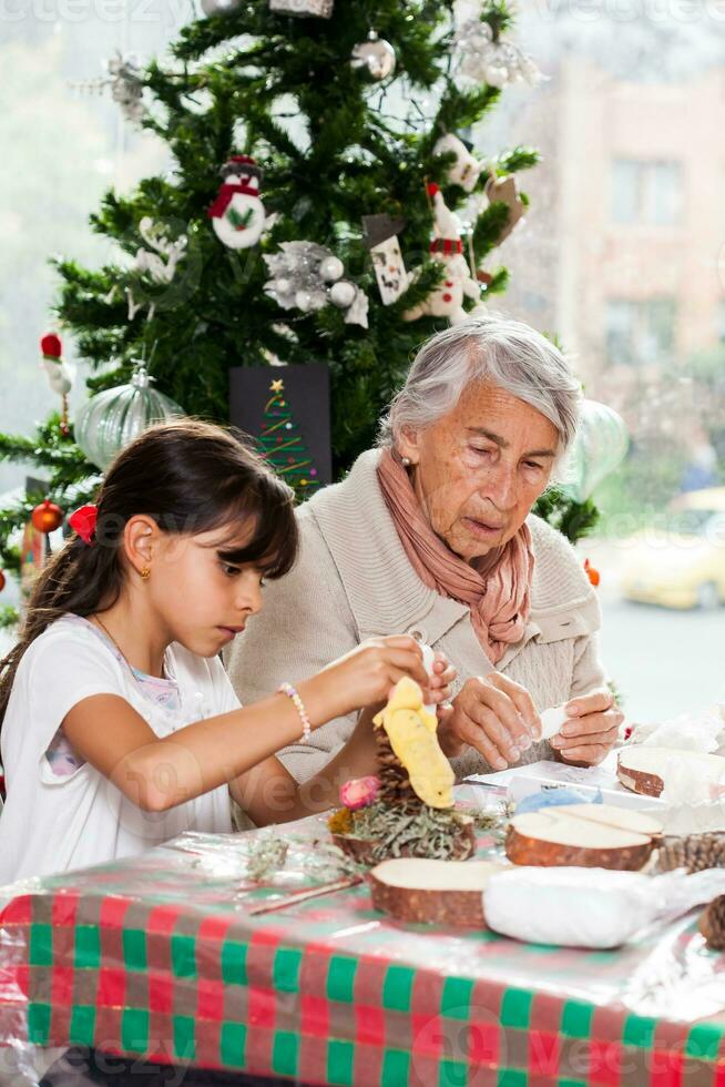 Grandmother teaching her granddaughter how to make christmas Nativity crafts - Real family photo