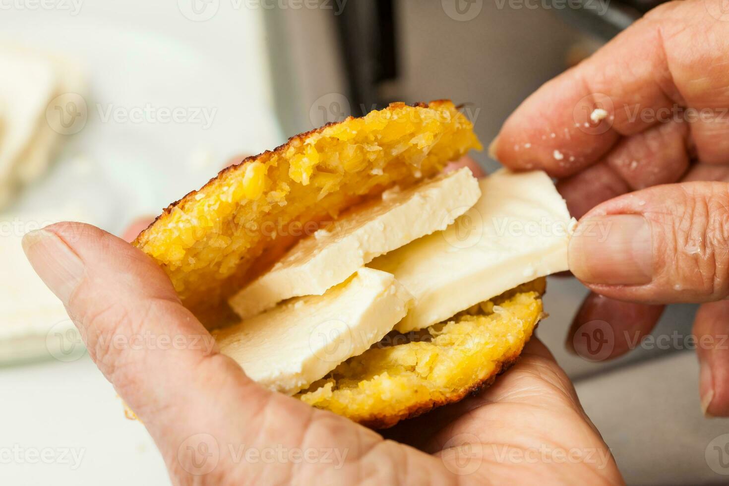 Traditional Colombian Arepa de Choclo Preparation. Stuffing the cooked corn bread with cheese photo