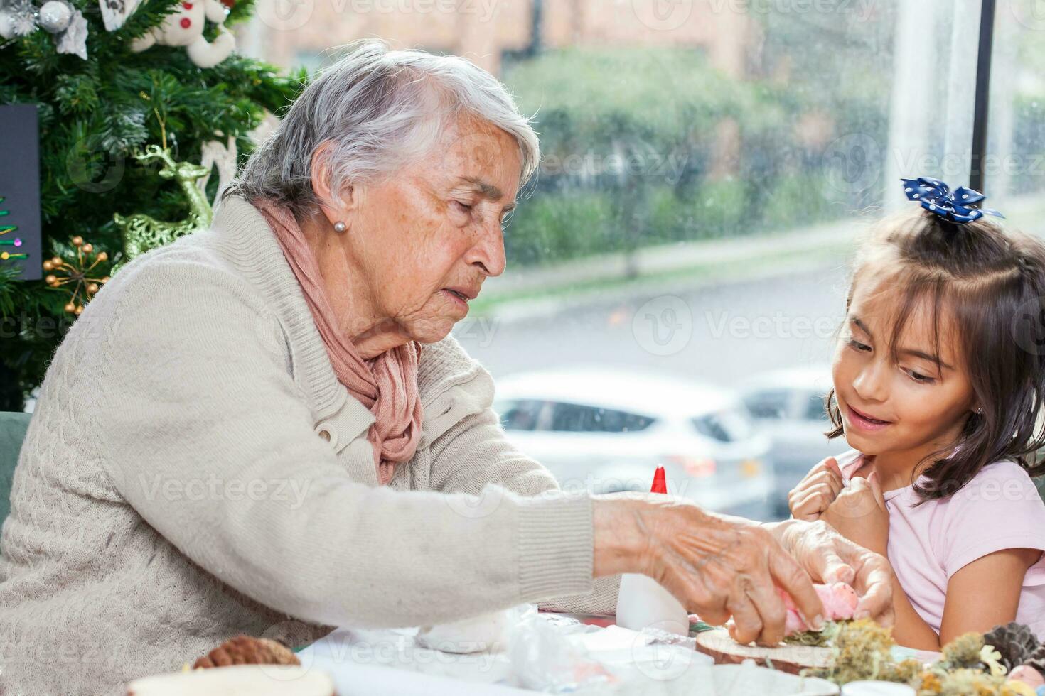 Grandmother teaching her granddaughter how to make christmas Nativity crafts - Real family photo