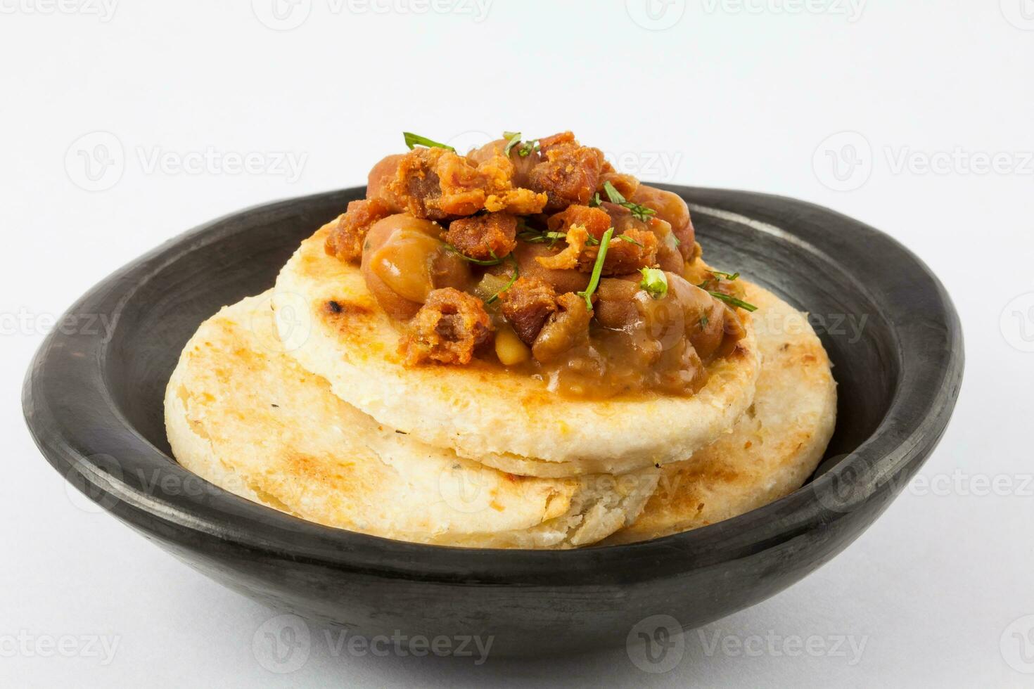 Traditional Colombian arepa topped with beans and pork rind photo