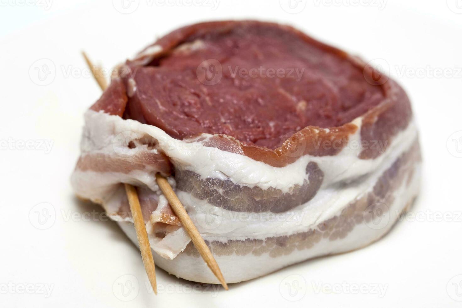 Raw beef tenderloin medallion wrapped in pork bacon. Filet mignon preparation. photo