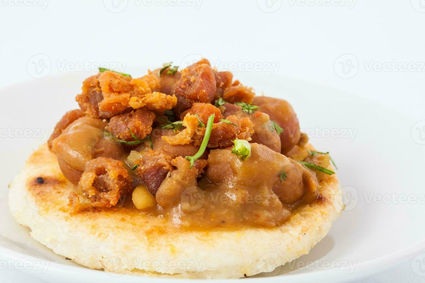 Traditional Colombian arepa topped with beans and pork rind photo