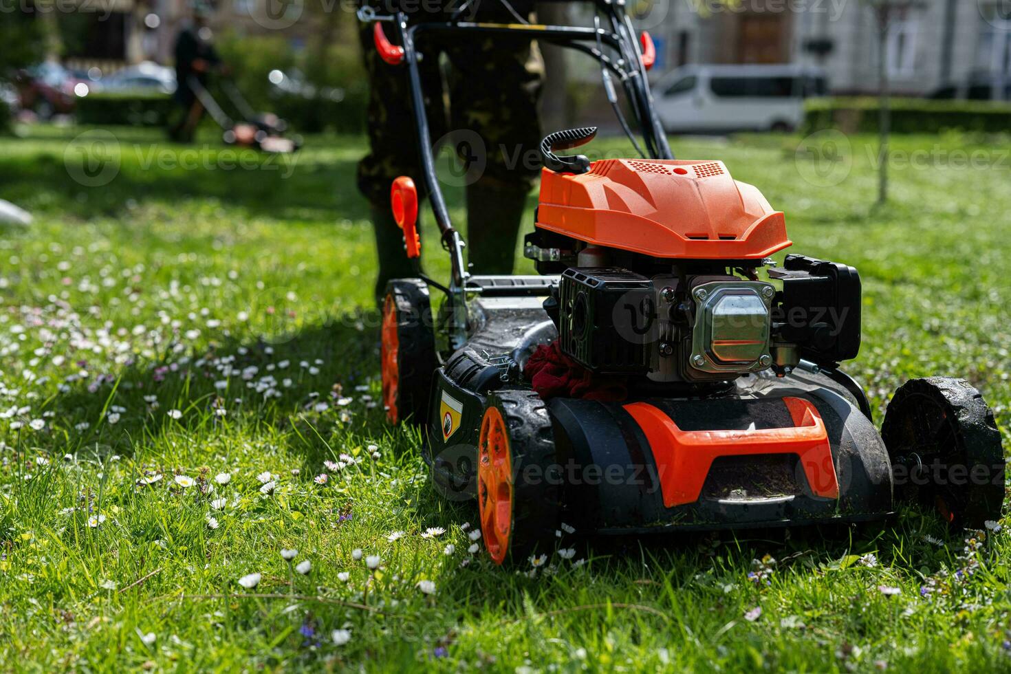 Communal services gardener worker man using lawn mower for grass cutting in city park. photo