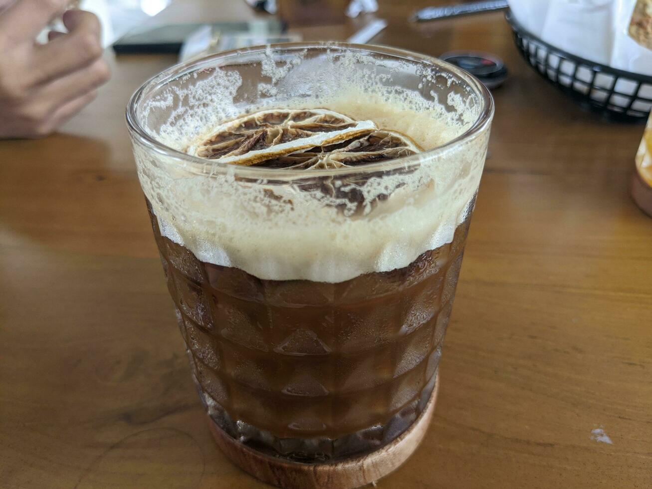 Arabica coffee ice with dried lemon slice with cream foaming. The photo is suitable to use for coffee shop background, menu poster and coffee content media.