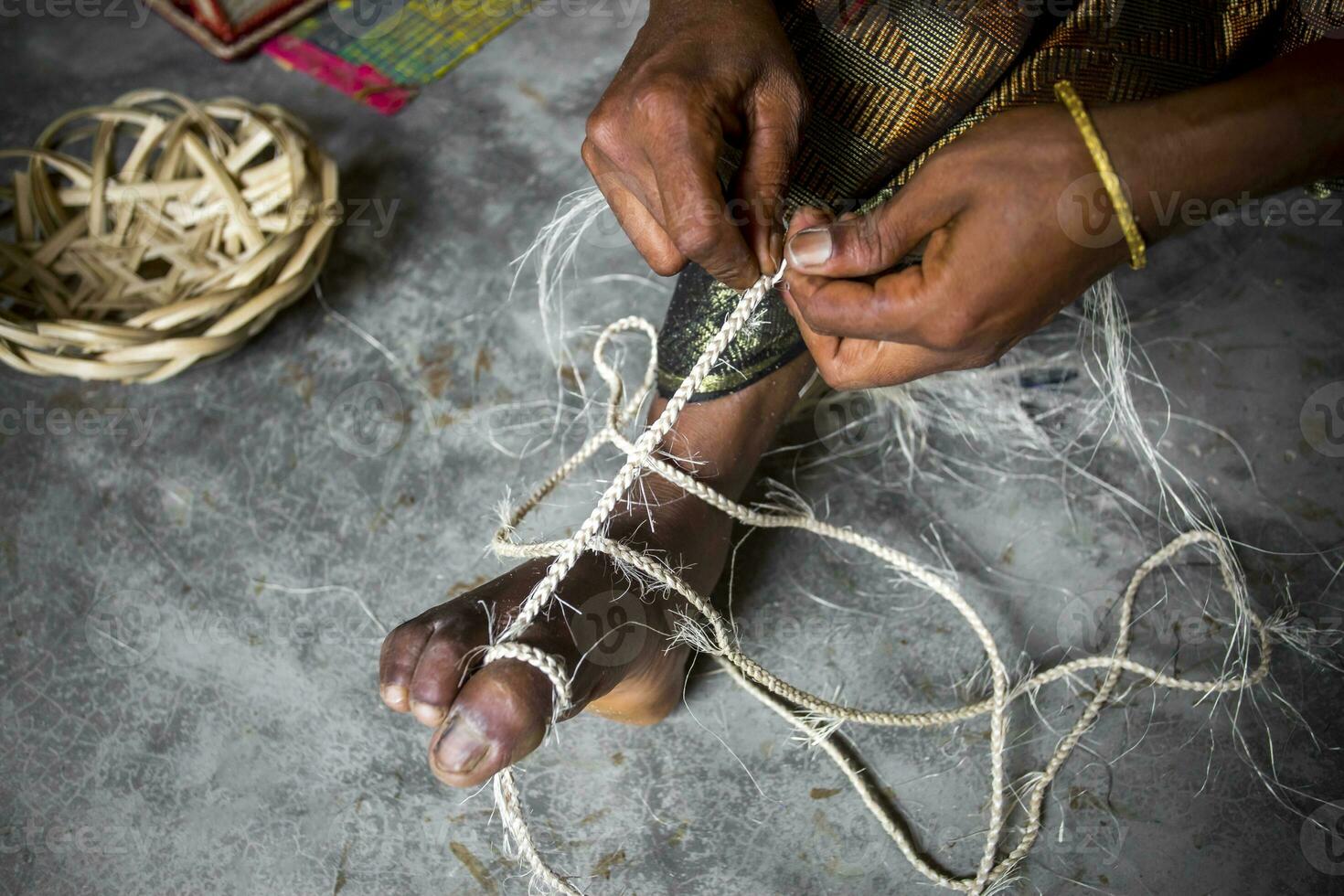 An woman is making a rope from the fibers of a banana tree with