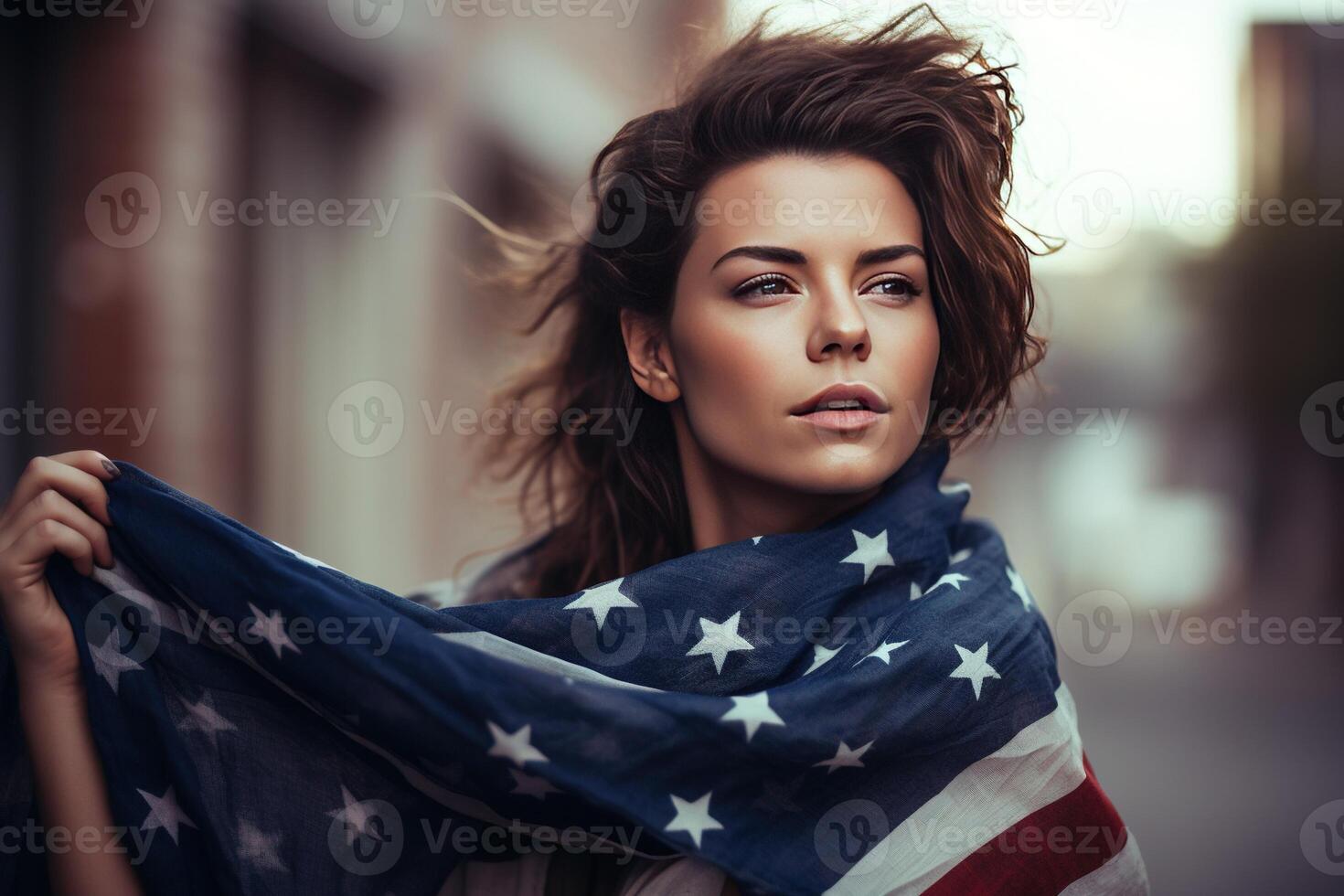 A beautiful young woman wrapped in an American flag on her neck in the field. photo