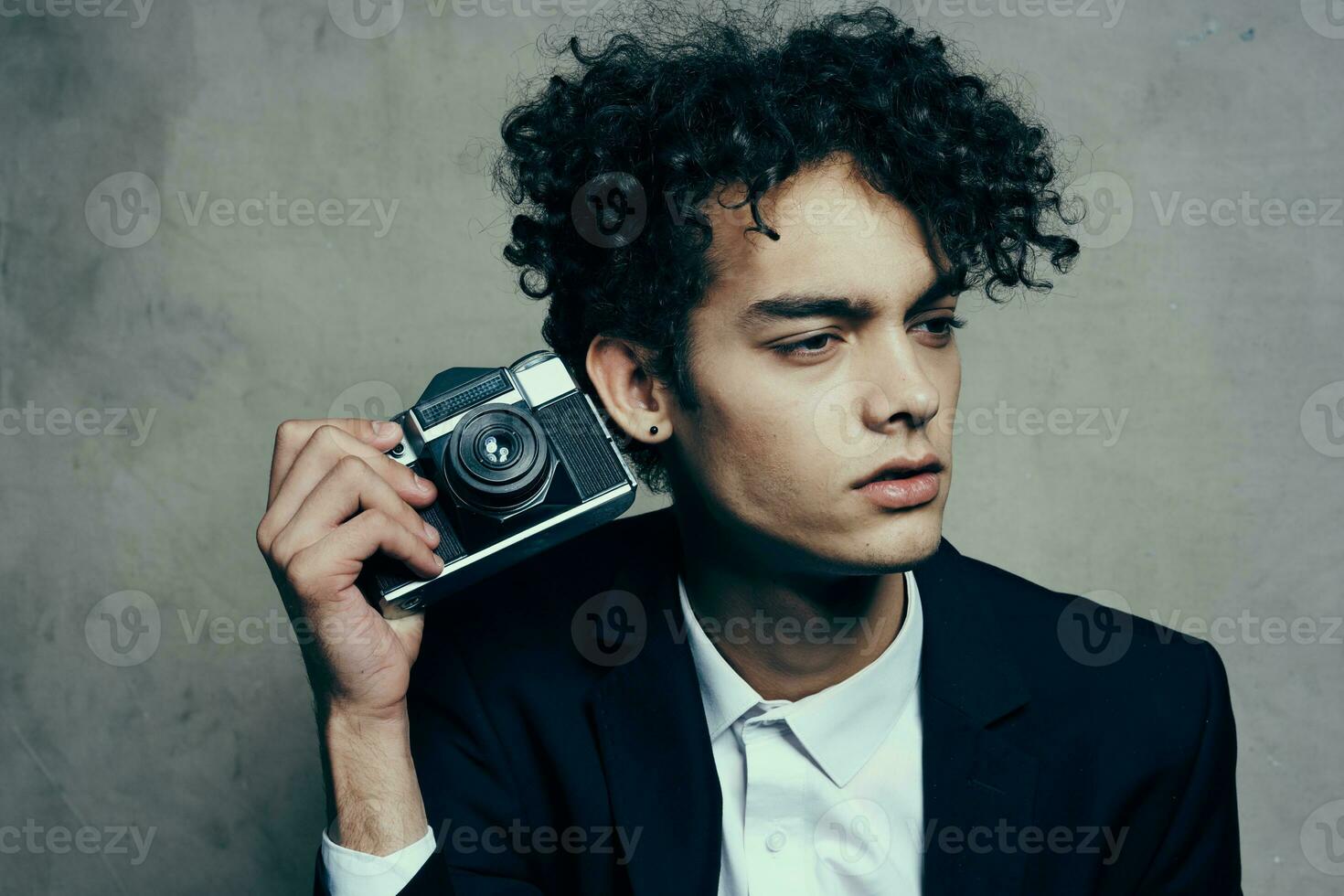 hermoso chico en un traje con un cámara lecciones Rizado pelo emociones modelo foto