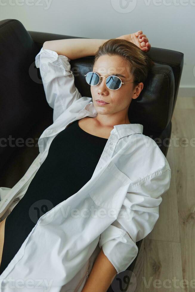 A woman lying on the couch with her glasses on and wriggling photo