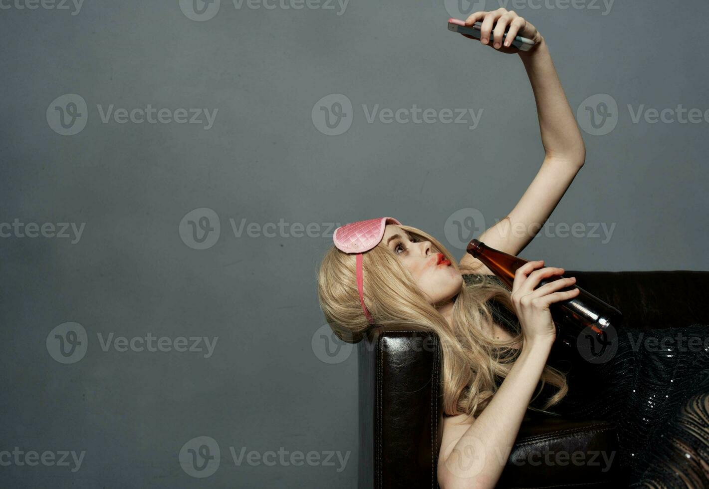 Drunk blonde woman in sleep mask with mobile phone photography model photo