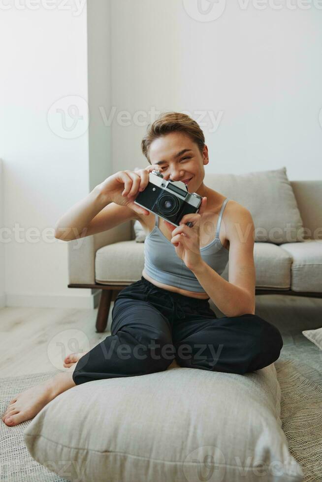 Happy smile woman holding an old camera and taking pictures of herself as a weekend photographer in home clothes with a short haircut hair without filters on a white background, free copy space photo