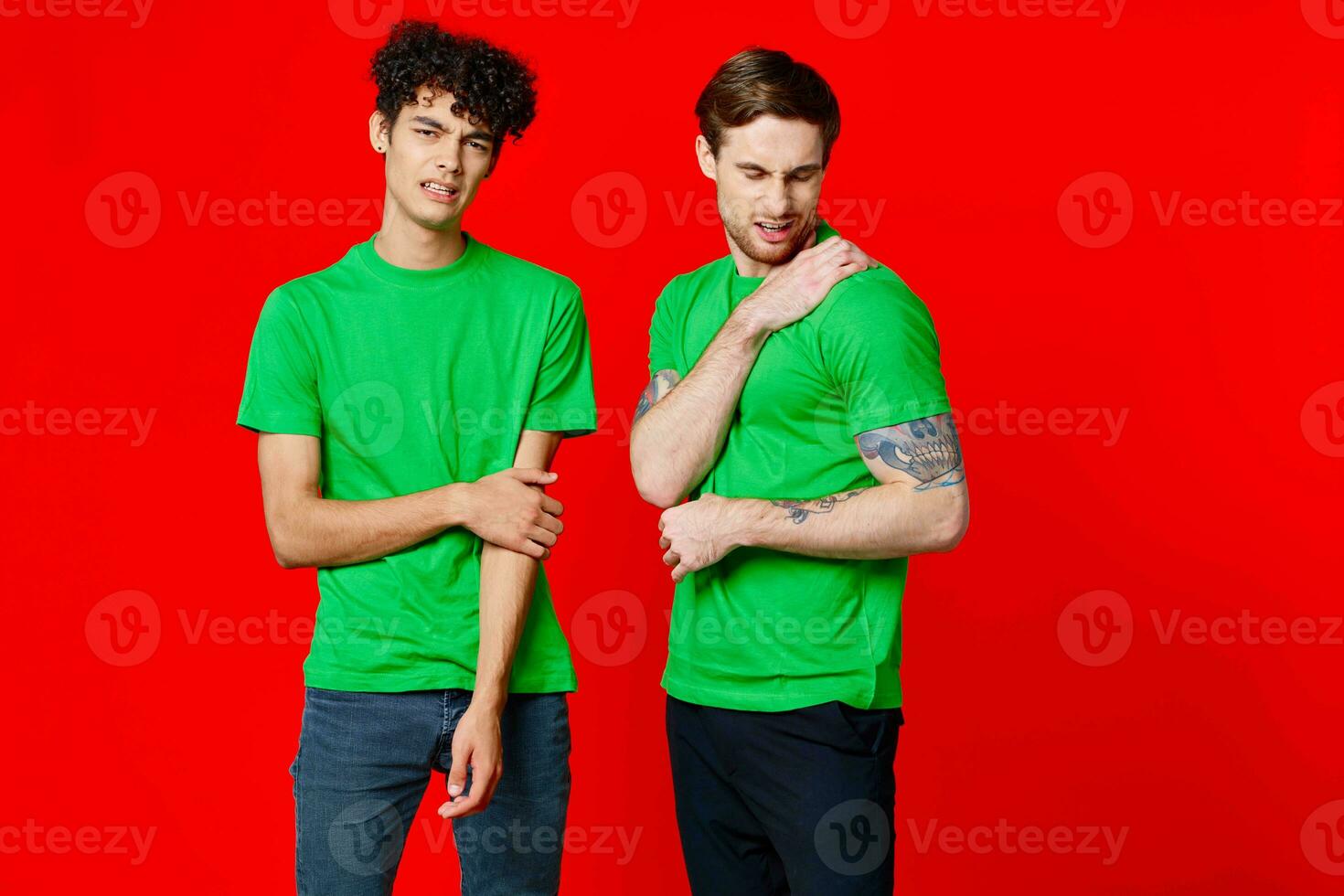 Two cheerful friends in green t-shirts communicating emotions red background photo