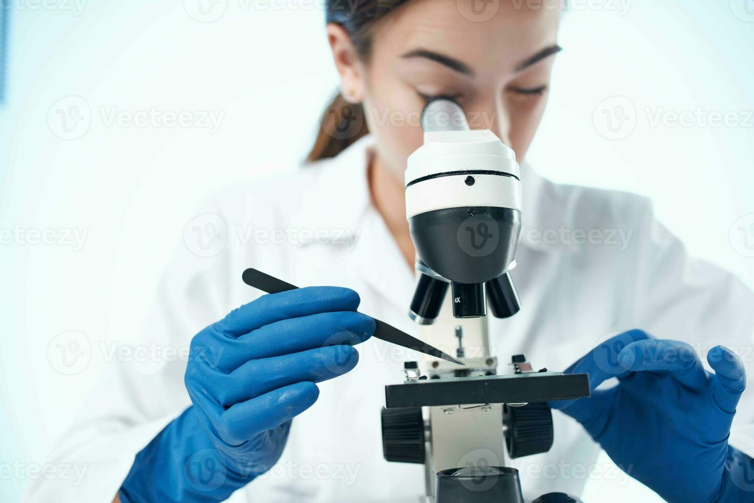 female laboratory assistant looking through a microscope research science technology photo