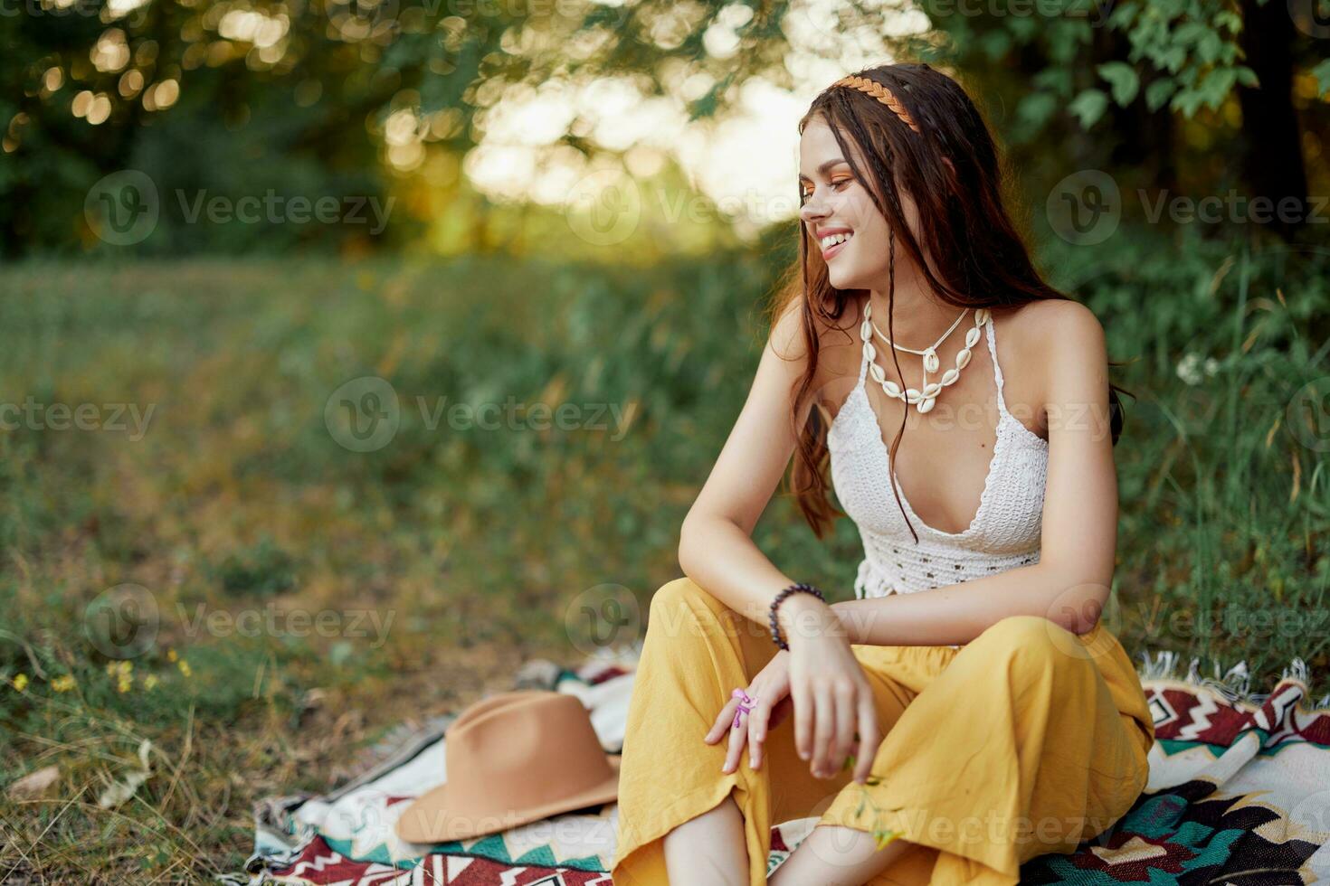 Girl dressed as a hippie eco relaxing in the park, sitting on a blanket in the sunset, relaxed lifestyle photo