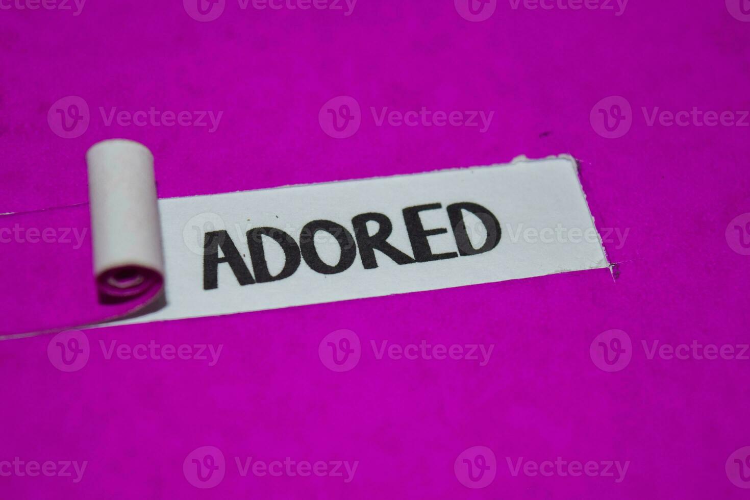 Adored text, Inspiration and positive vibes concept on purple torn paper photo
