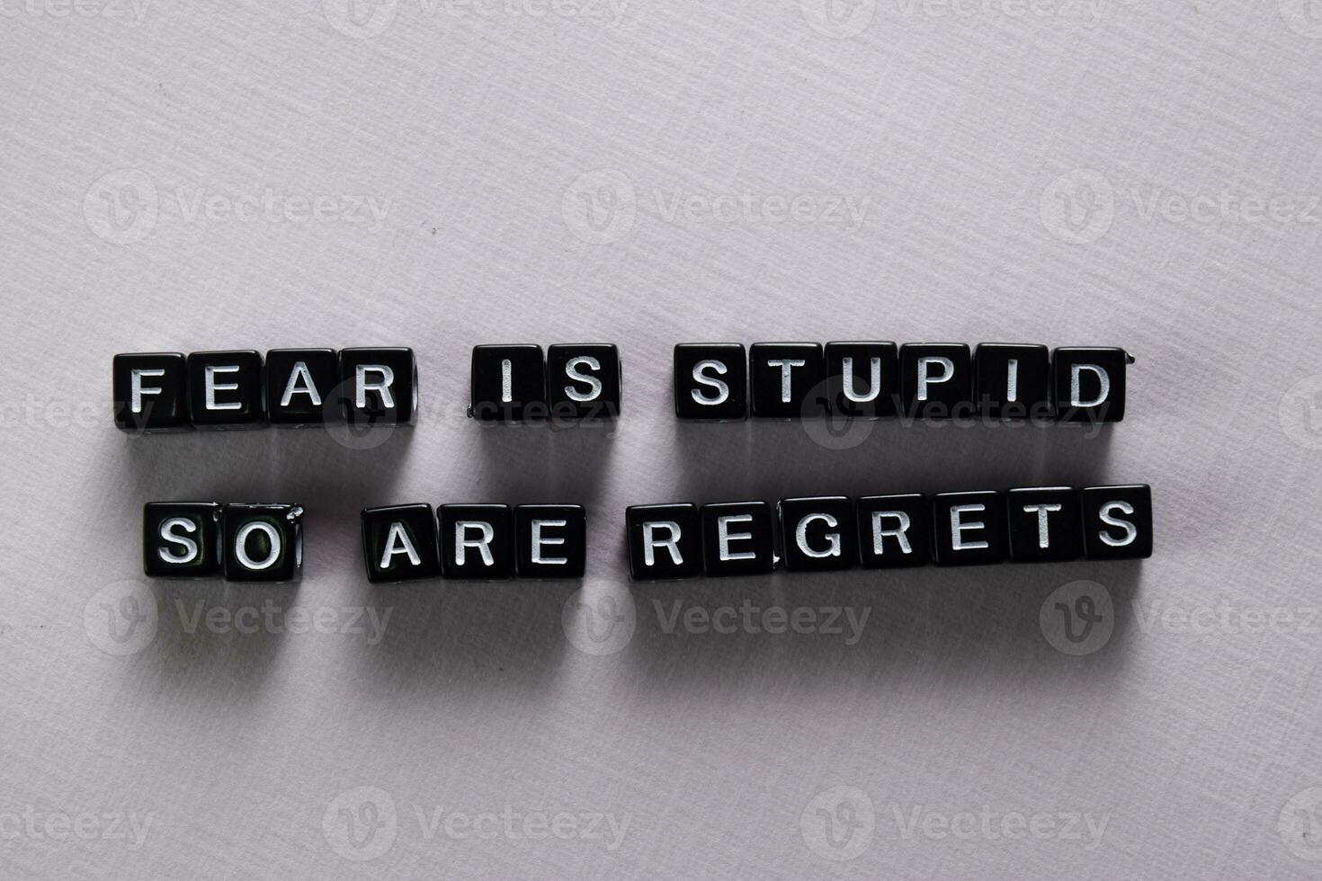 Fear is stupid so are regrets on wooden blocks. Motivation and inspiration concept photo